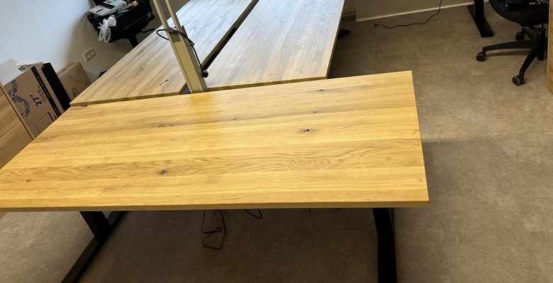 Elf h&ouml;henverstellbare Massivholz-Schreibtische mit Eckelement bei der B&uuml;romontage